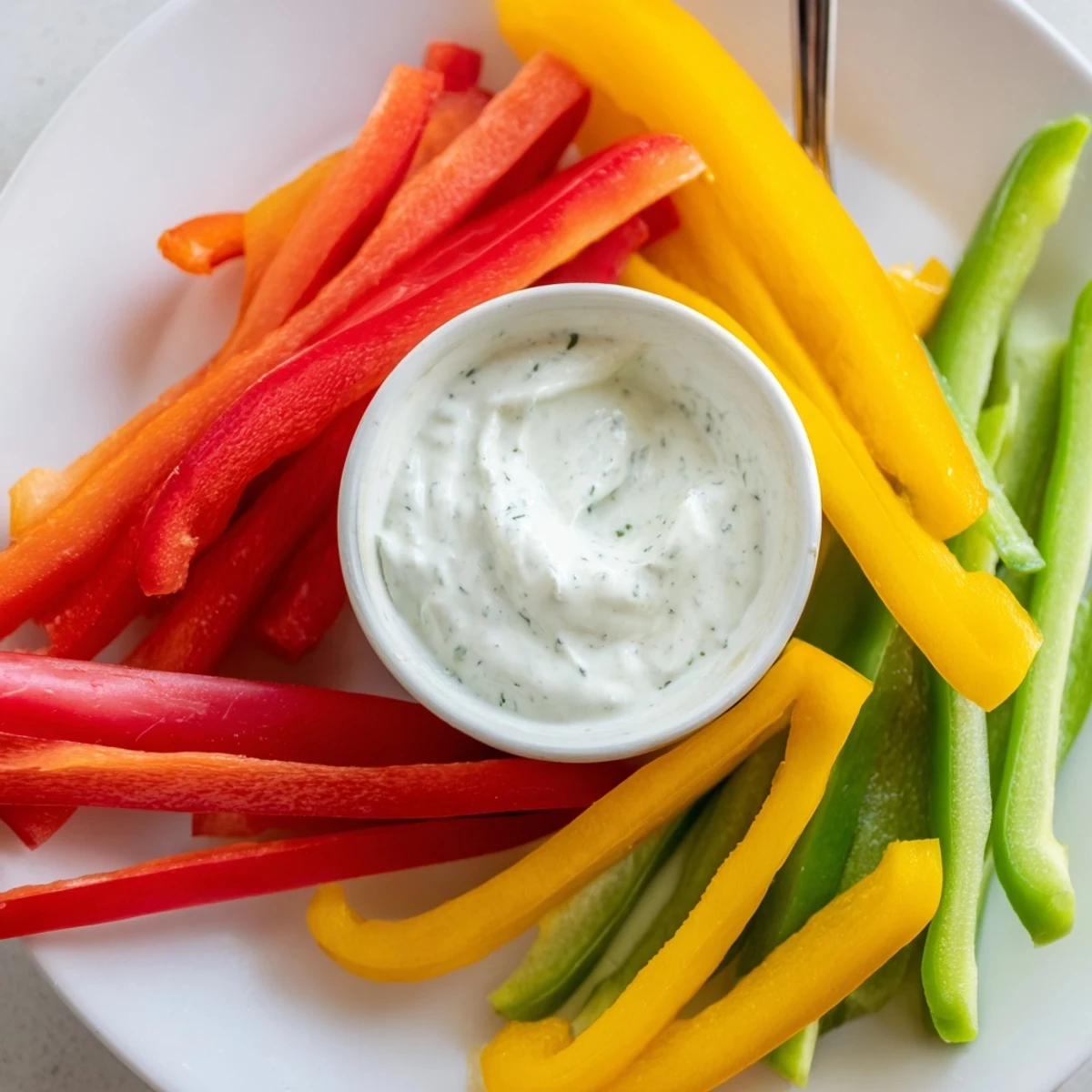 Crisp bell pepper strips surround creamy Greek yogurt dip, a refreshing and flavorful snack.
