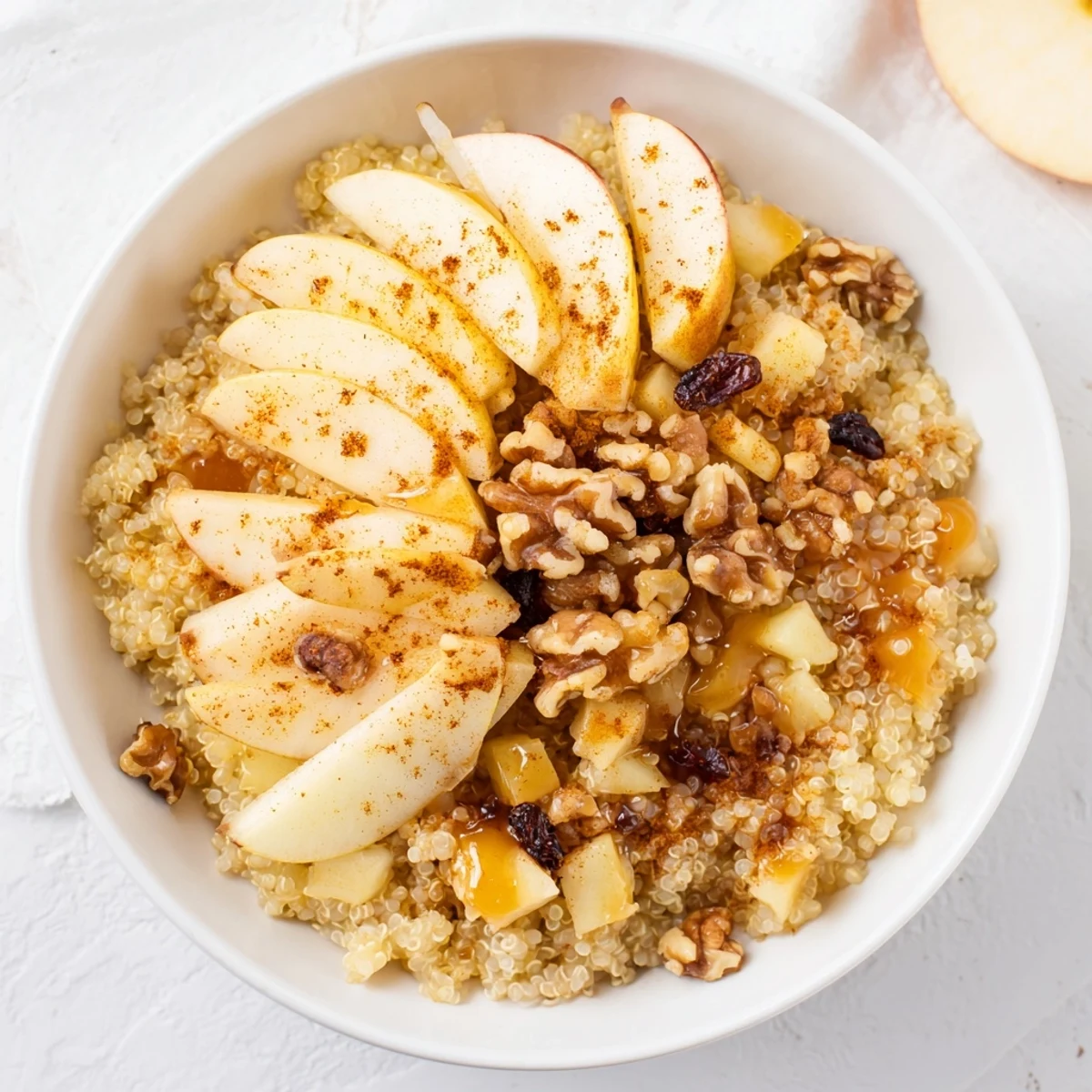 Warm and inviting apple cinnamon quinoa bowl, perfect for a cozy, healthy breakfast, topped with nuts.