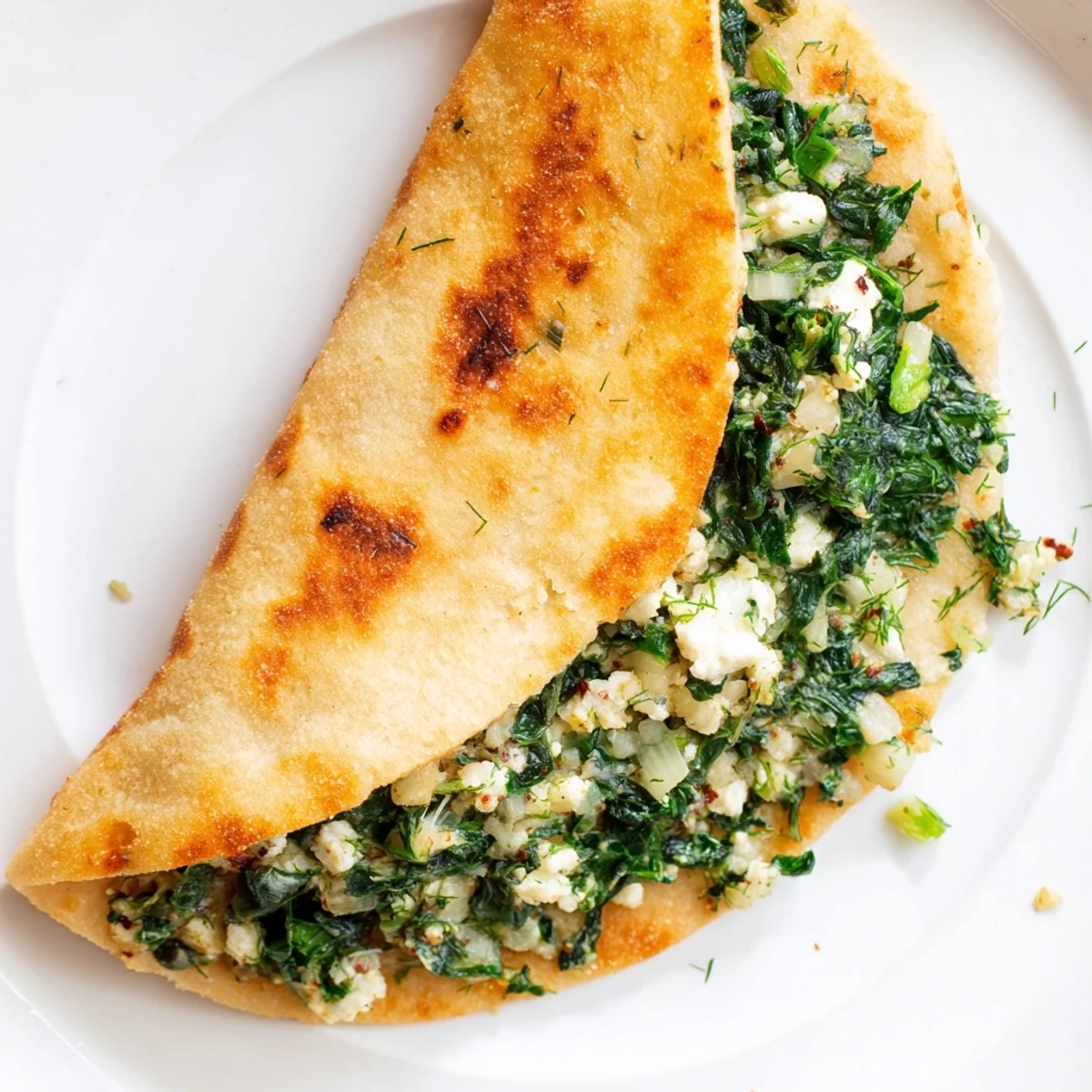 A close-up of freshly baked Turkish Spinach & Feta Flatbread with visible spinach and cheese filling.