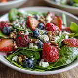 Der Spinat-Beeren-Salat mit saftigen Beeren und Honig-Senf-Vinaigrette glänzt im Sonnenlicht.