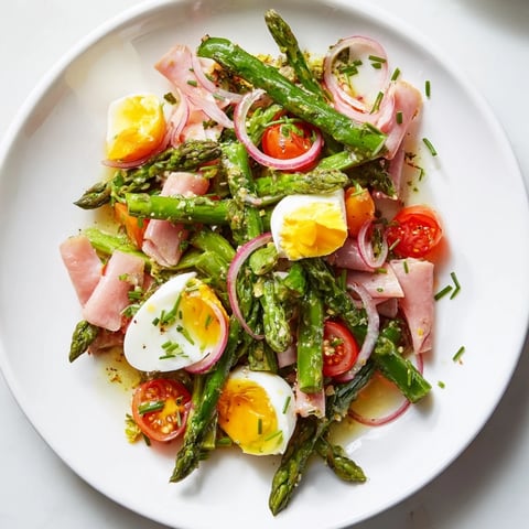 Frischer Asparagussalat mit ham und Eiern, serviert mit einem würzigen Dressing.
