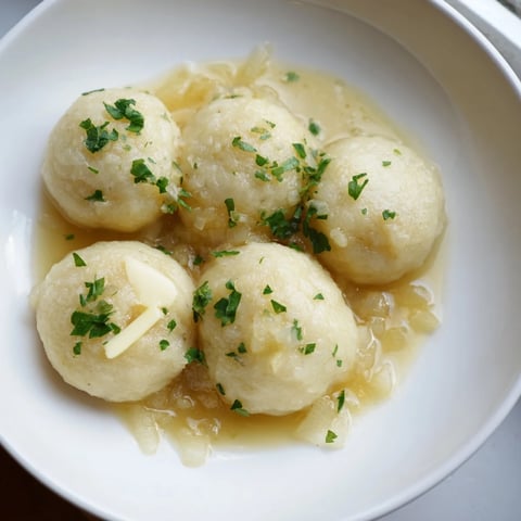 A comforting plate of Kartoffelklöße, swimming in rich sauce, alongside colorful vegetables.