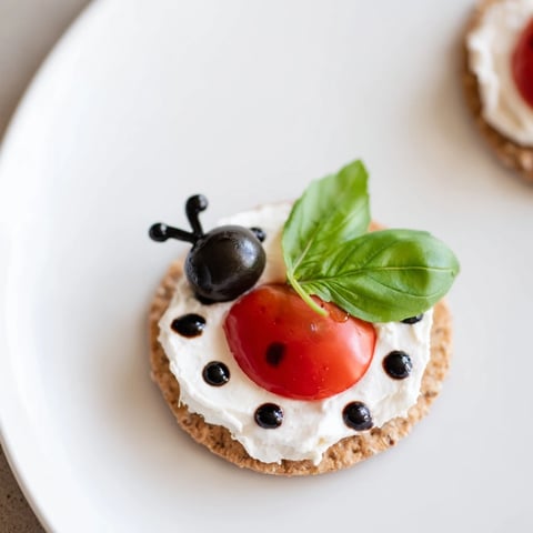"Ladybug Love Picnic Finger Foods: vibrant cherry tomatoes and olives create charming ladybug appetizers."