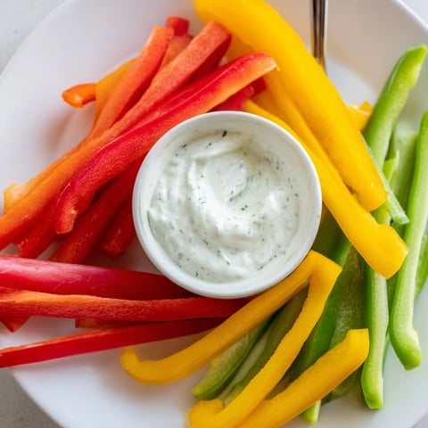Crisp bell pepper strips surround creamy Greek yogurt dip, a refreshing and flavorful snack.