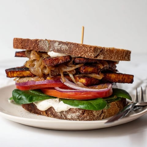 Köstliche Räucherspeck-Tempeh- und Kümmelsauerkraut-Sandwiches auf rustikalem Brot serviert  