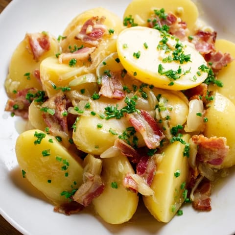 Tender potatoes in a light vinegar dressing create this flavorful warm German potato salad.