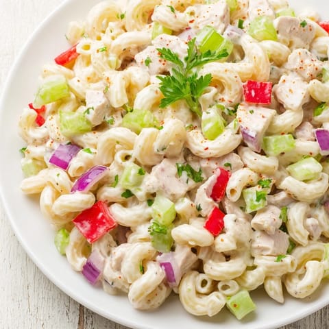 This Chicken Macaroni Holiday Salad features a close-up of colorful vegetables and creamy dressing.